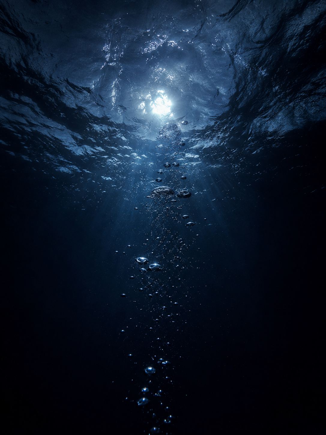 Underwater view of bubbles rising toward moonlit surface